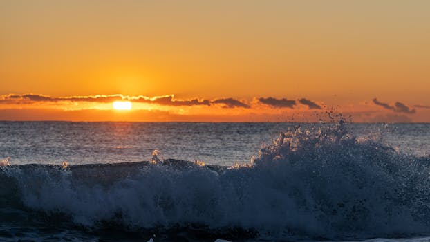 Breathtaking sunset in Valencia with vivid orange hues and splashing ocean waves, capturing nature's beauty.