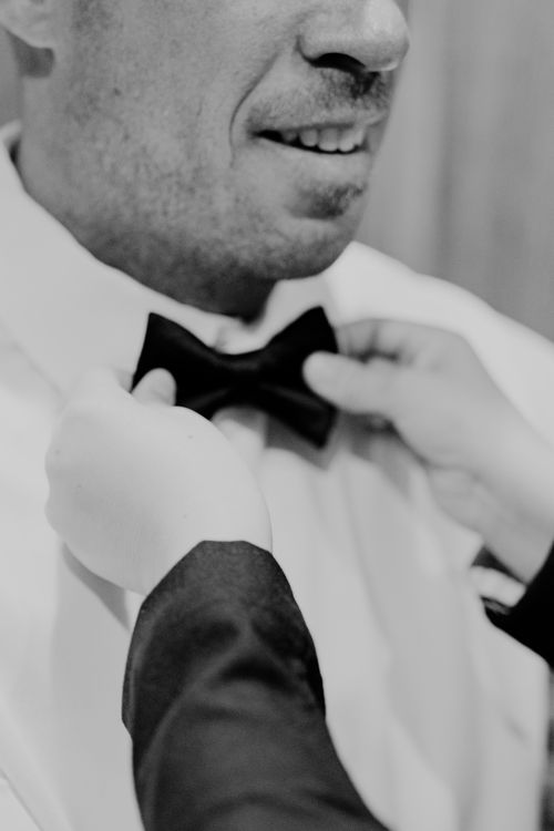 Free Close-up of hands adjusting a bow tie on a man's shirt in black and white. Stock Photo