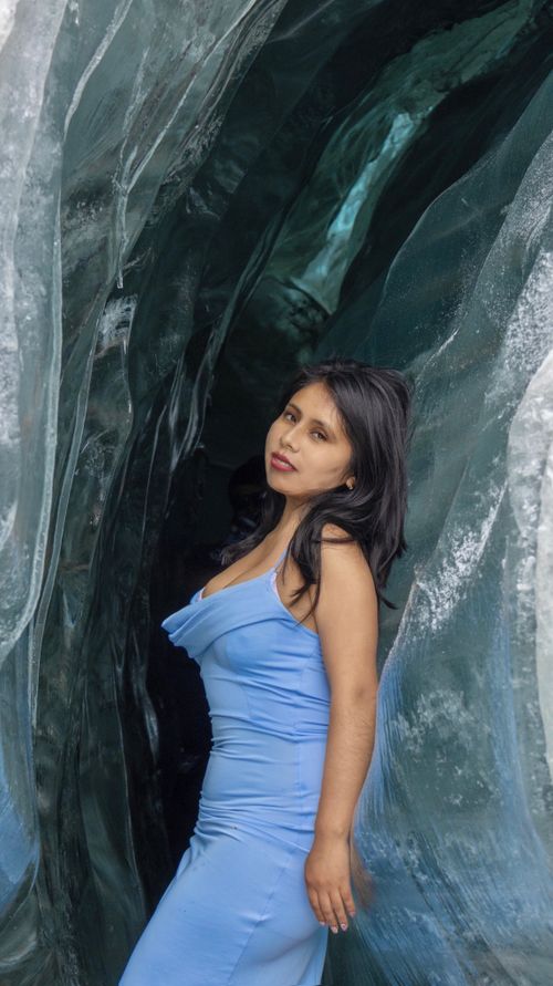 Free A woman poses gracefully in a blue dress within an expressive ice cave setting. Stock Photo