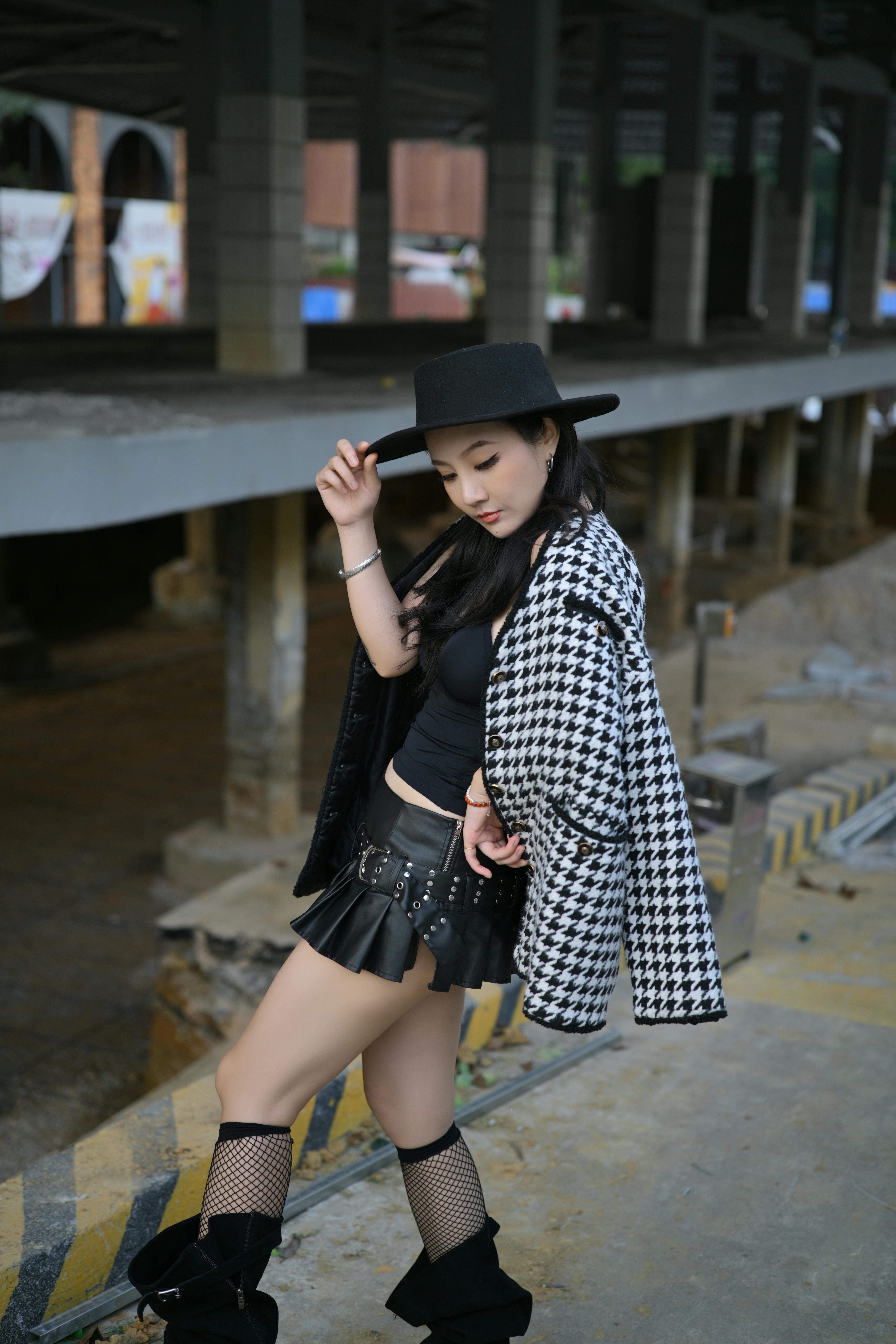 Stylish woman posing in a chic outfit in a city underpass.