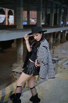 Stylish woman posing in a chic outfit in a city underpass.