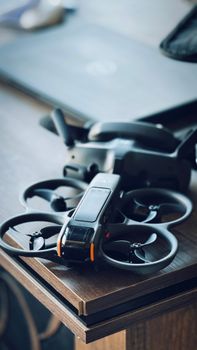 A compact drone with modern design resting on a wooden table indoors.