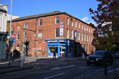 Free A classic brick building on a bustling street corner under a bright blue sky. Stock Photo