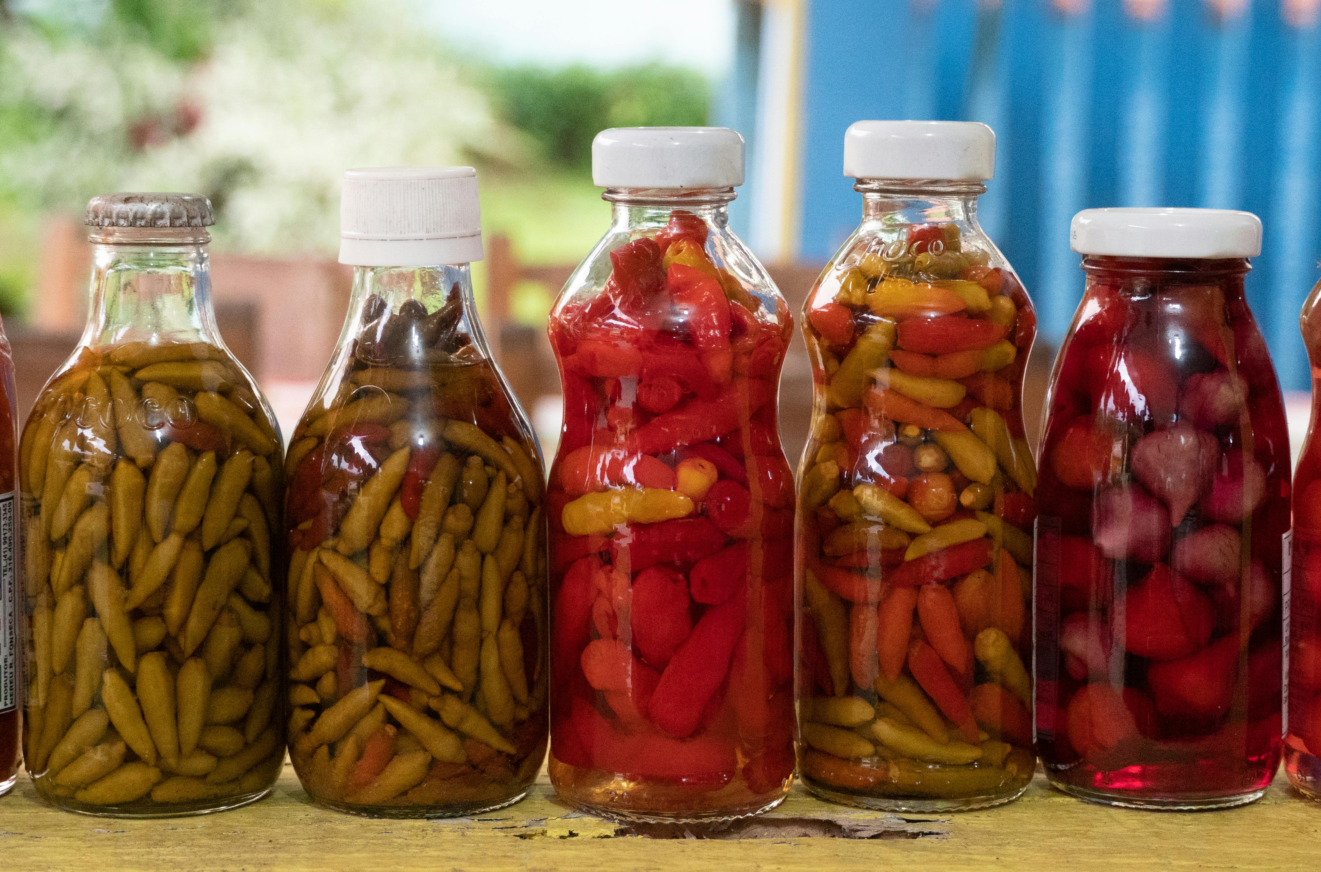 Close-up of vibrant pickled peppers in glass bottles captured in Morretes, Brazil.
