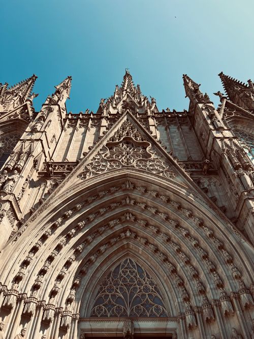 Gratis Detaljert utsikt over fasaden til den gotiske katedralen i Barcelona under en klar blå himmel. Arkivbilde
