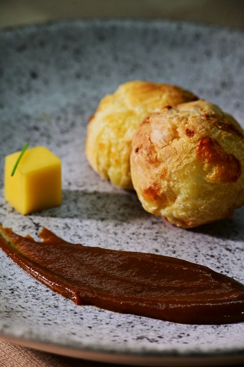 Free Elegant presentation of cheese puffs with sauce and garnish on a speckled plate. Stock Photo