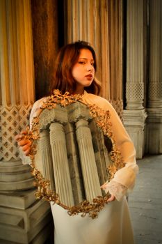 Woman holding ornate mirror reflecting columns, blending elegance with architecture.
