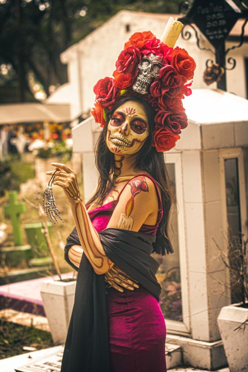 Free A woman adorned in colorful catrina makeup and headdress in a Mexican cemetery for Día de Muertos. Stock Photo