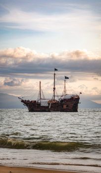A vintage pirate ship sails the sea at twilight, capturing a classic maritime scene.