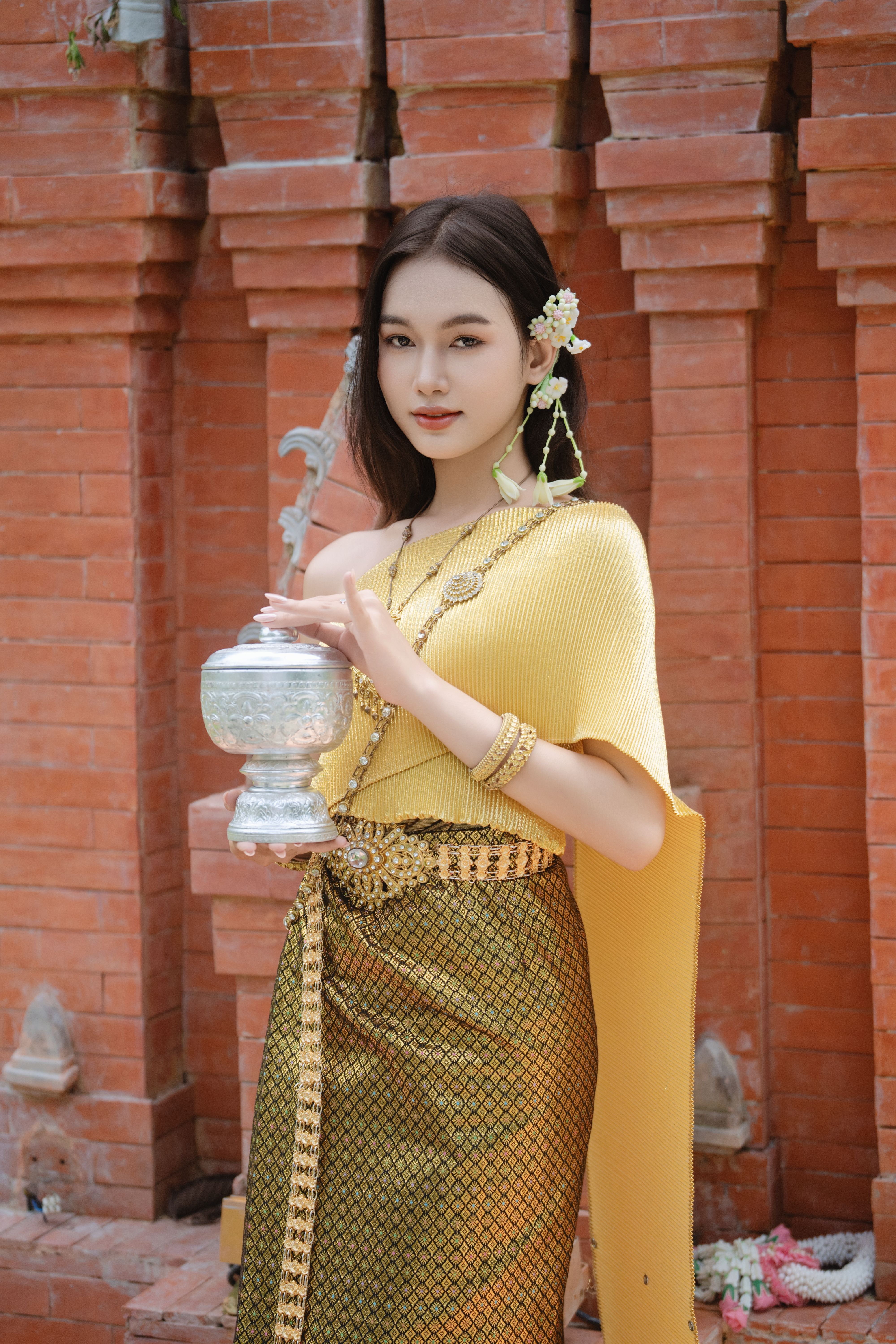 Portrait of a woman in traditional attire holding a decorative silver jar.