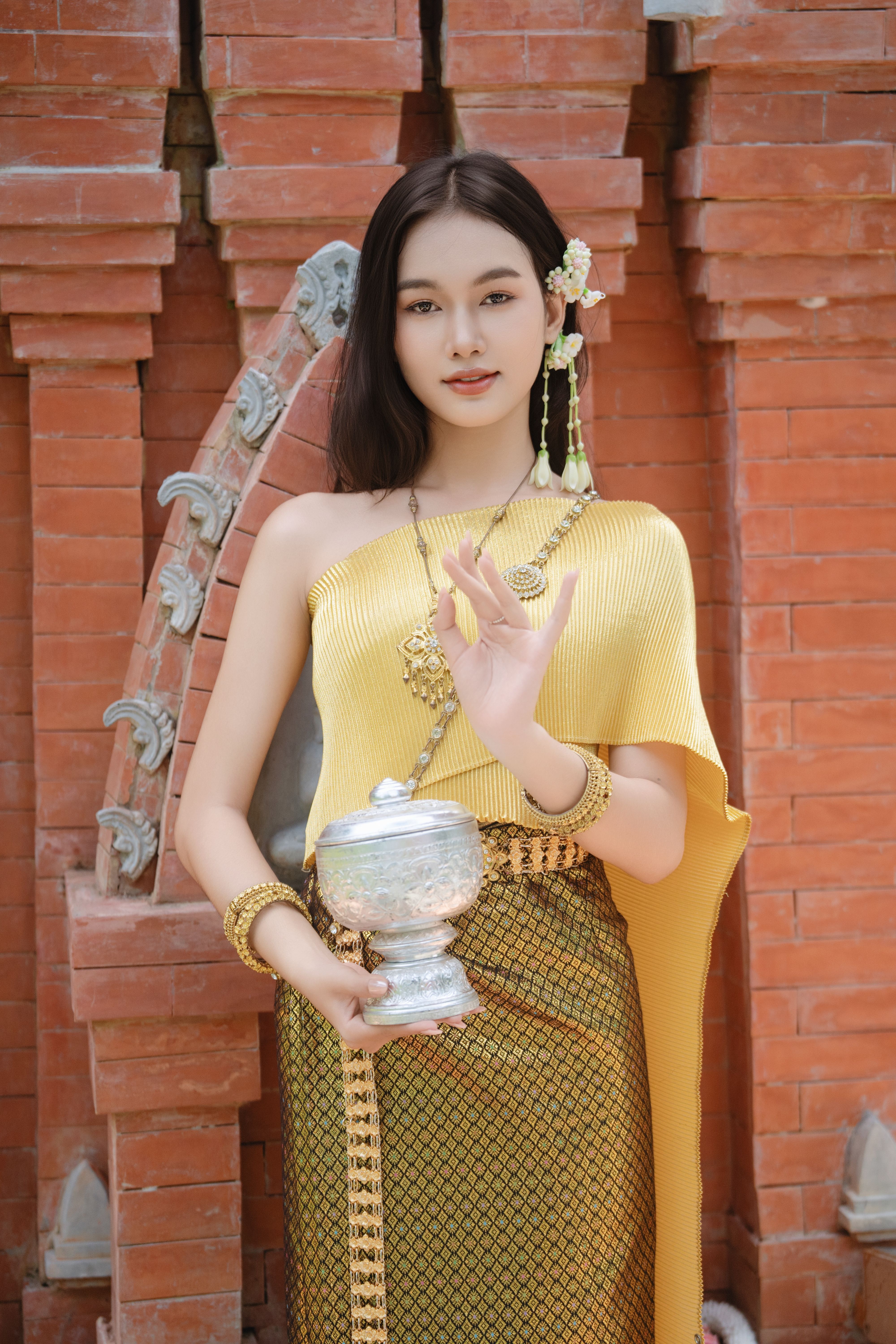Elegant portrait of a woman in traditional Khmer dress holding a silver container.