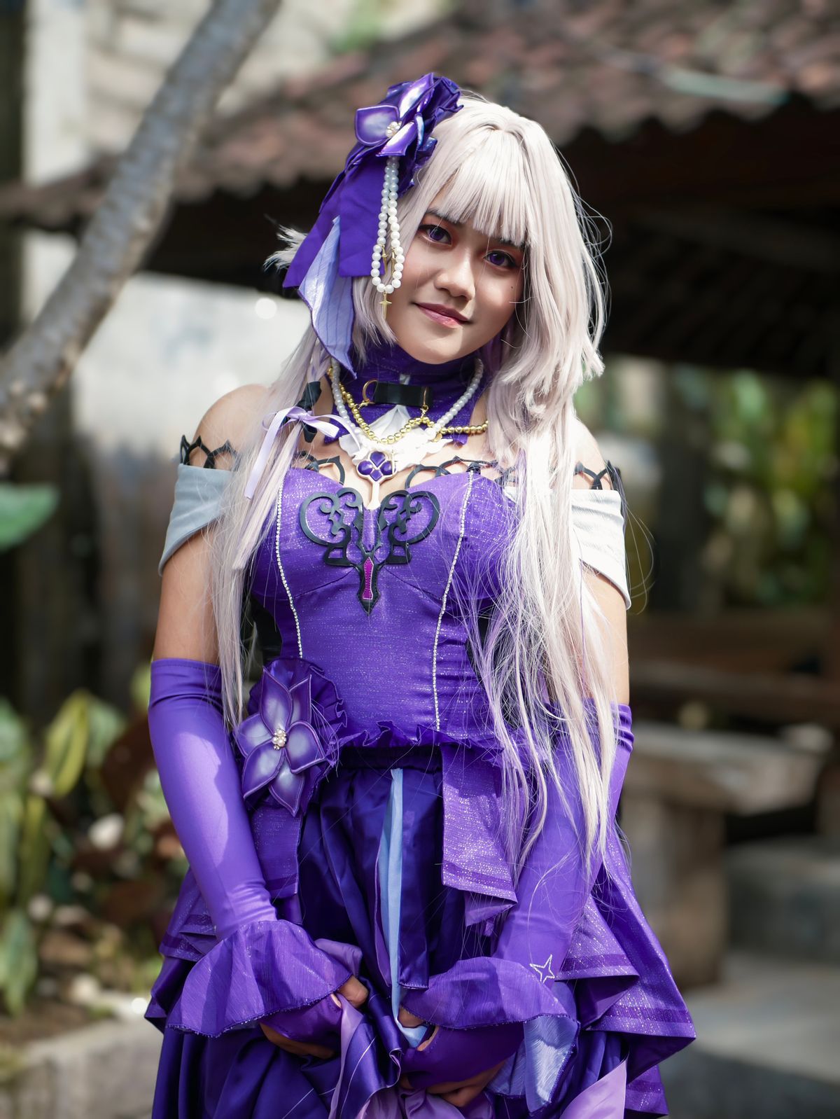 Anime character cosplayer in a purple costume posing outdoors