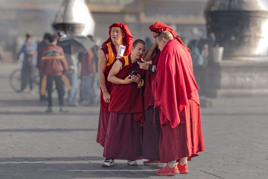 Three monks in traditional attire gather outdoors, sharing a conversation in a serene, focused moment.