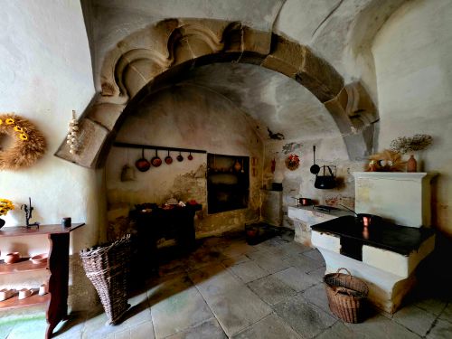 Free Charming rustic stone kitchen with vintage decor, warm tones, and an antique hearth. Stock Photo