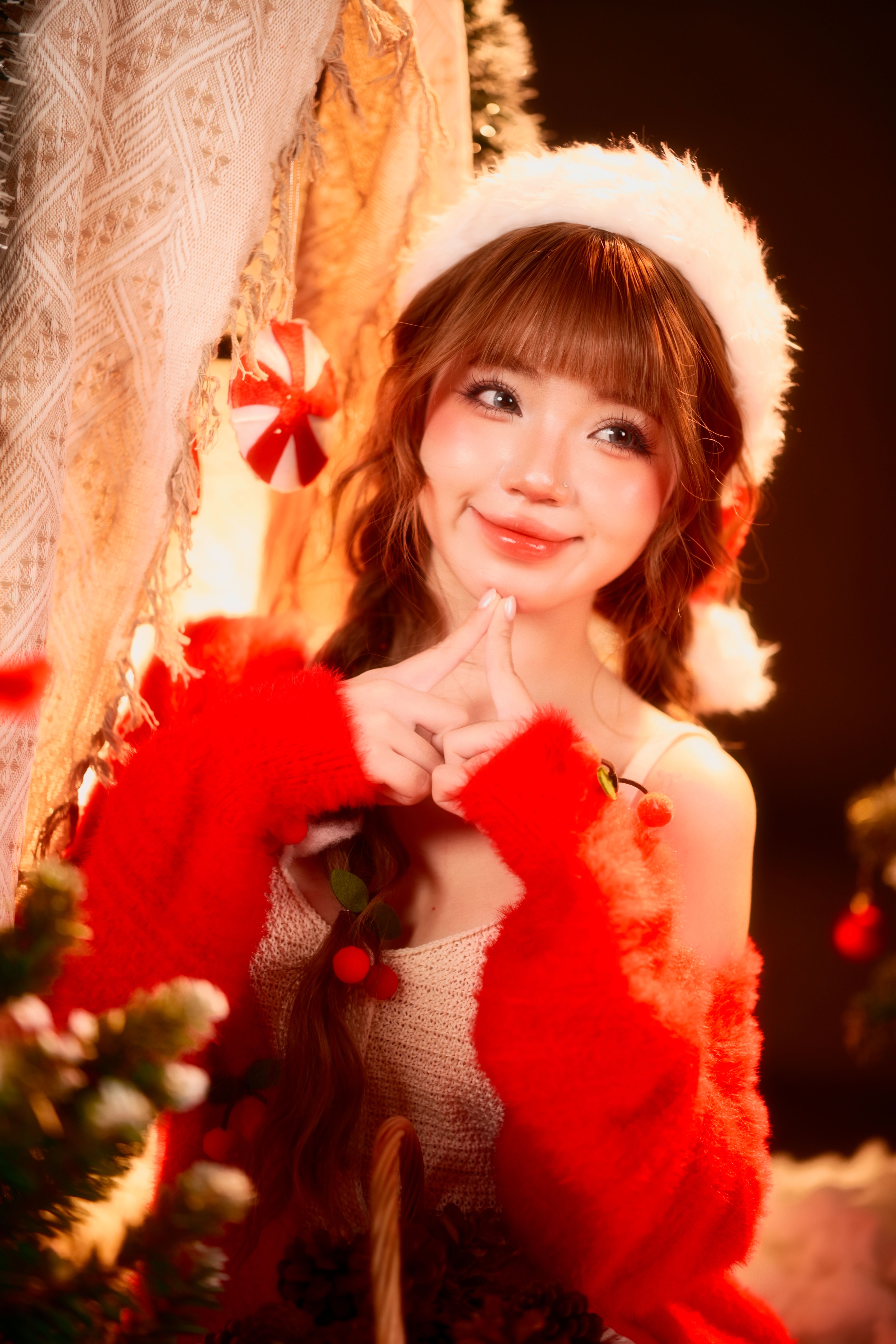 A joyful woman in a Santa hat surrounded by festive holiday decorations.