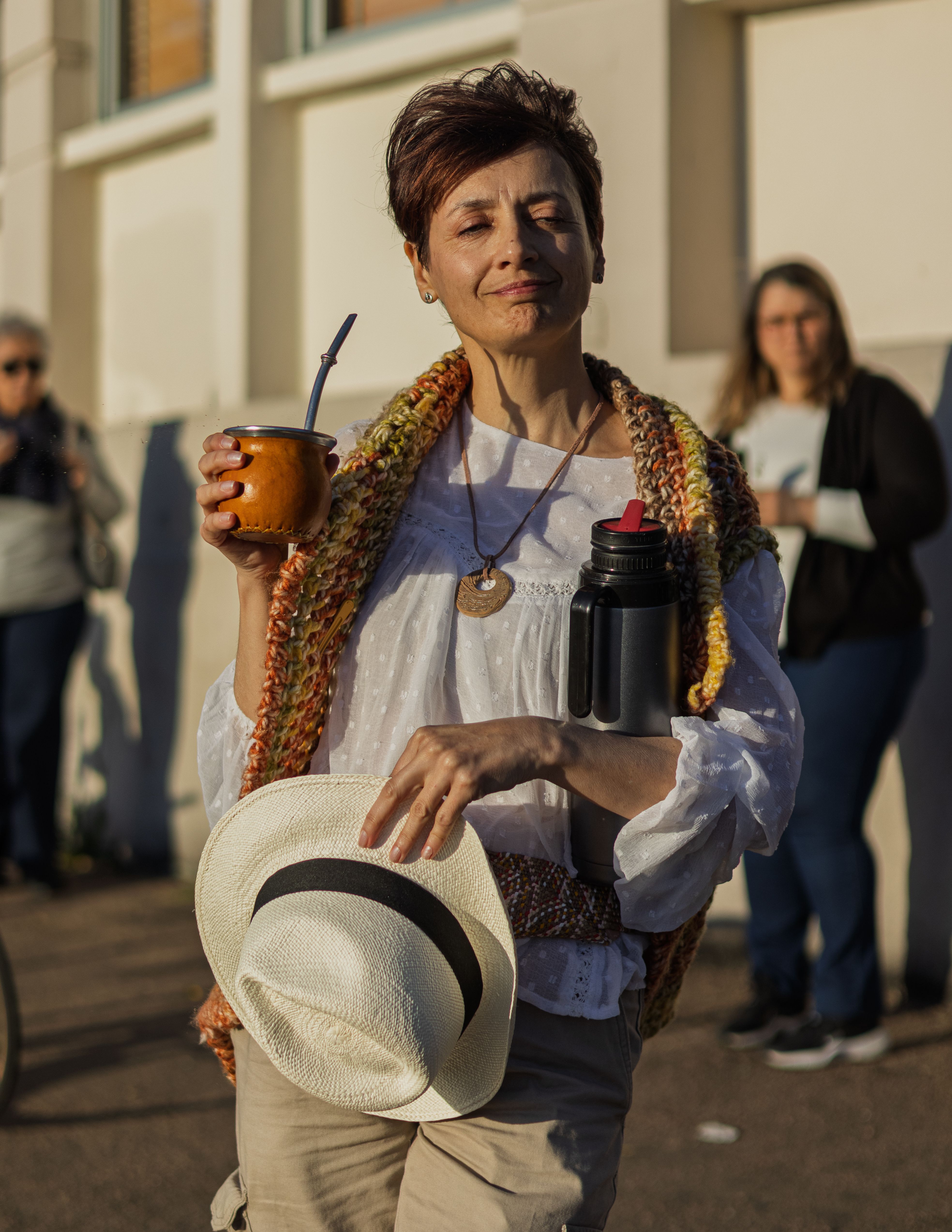 A woman in Montevideo enjoys yerba mate outdoors with a traditional flask, embracing local culture.