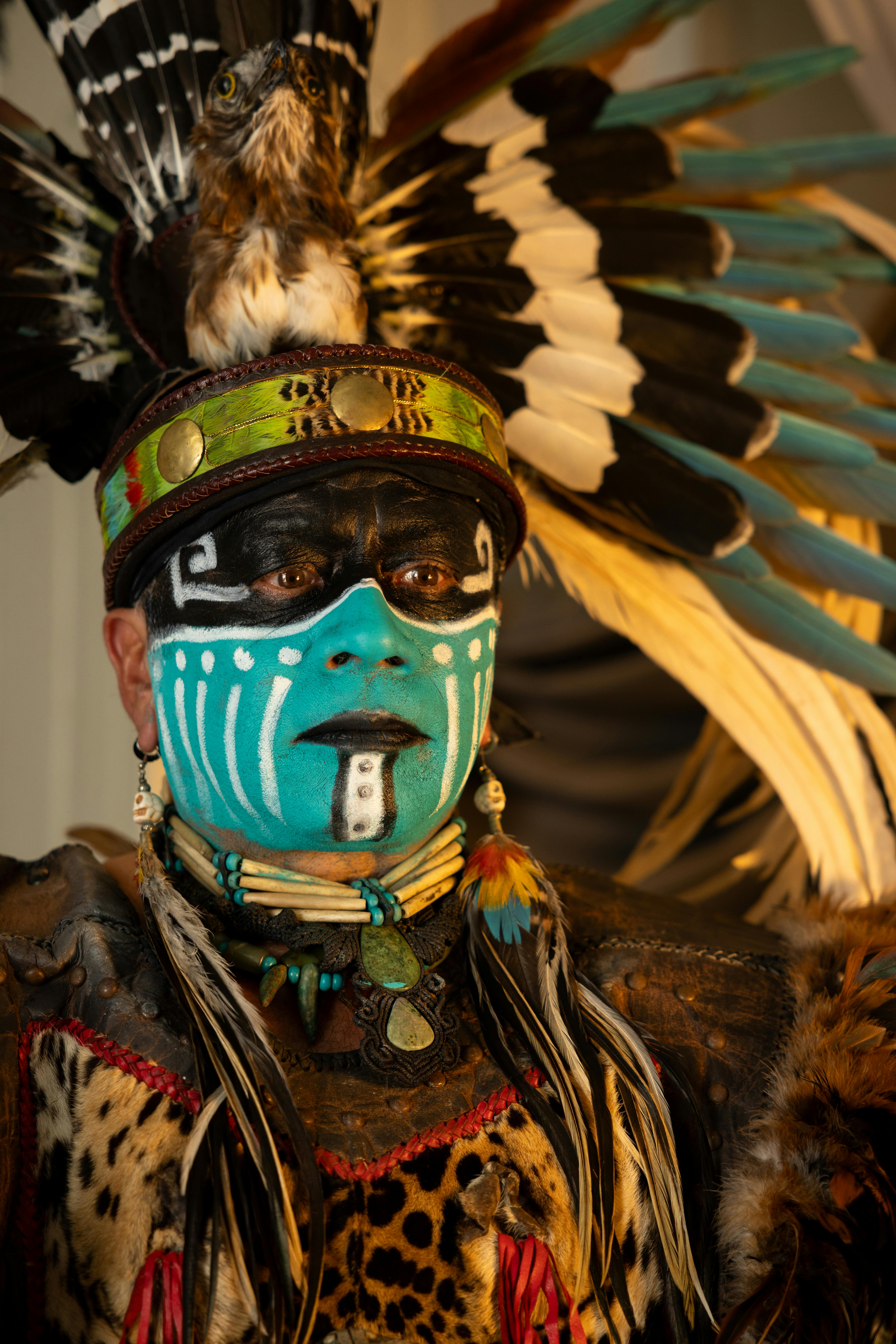 Portrait of a person in vibrant Native American traditional attire and face paint.