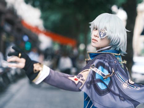 Cosplayer poses in a detailed fantasy costume on a busy street, creating an artistic scene.