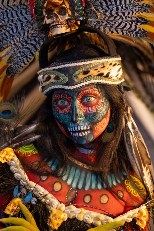 Free Colorful Day of the Dead costume and face paint adorned with feathers and skulls. Stock Photo