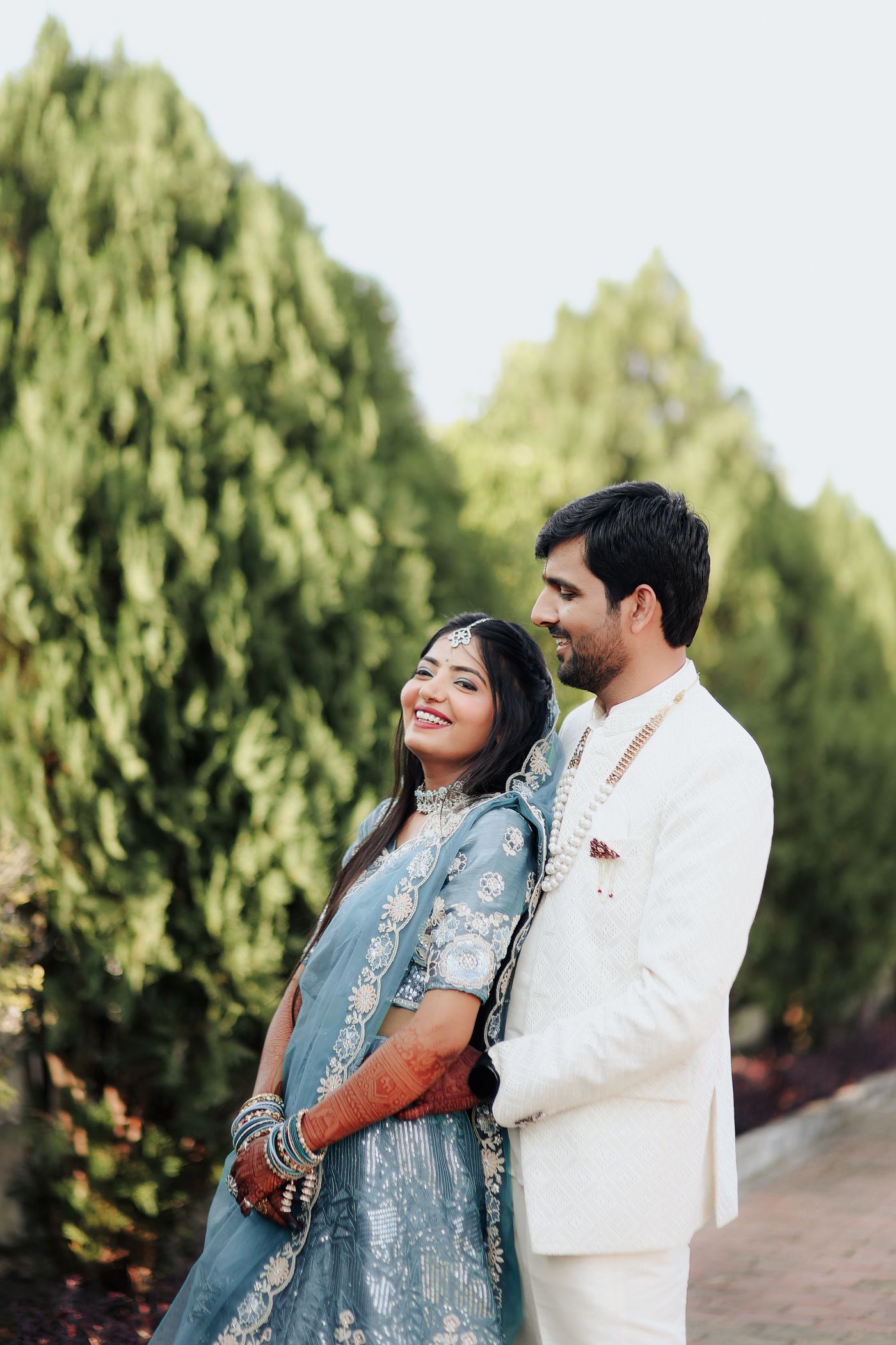 Elegant Indian wedding couple sharing a joyful outdoor portrait