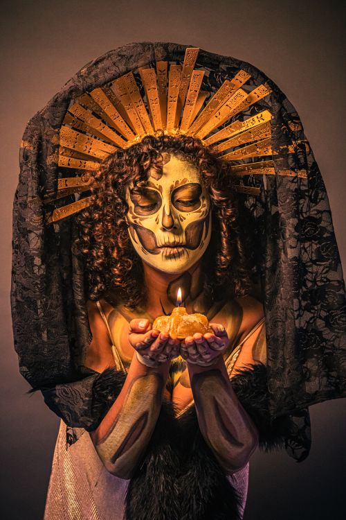 Free Catrina with ornate headdress holding a candle for Día de Muertos. Stock Photo