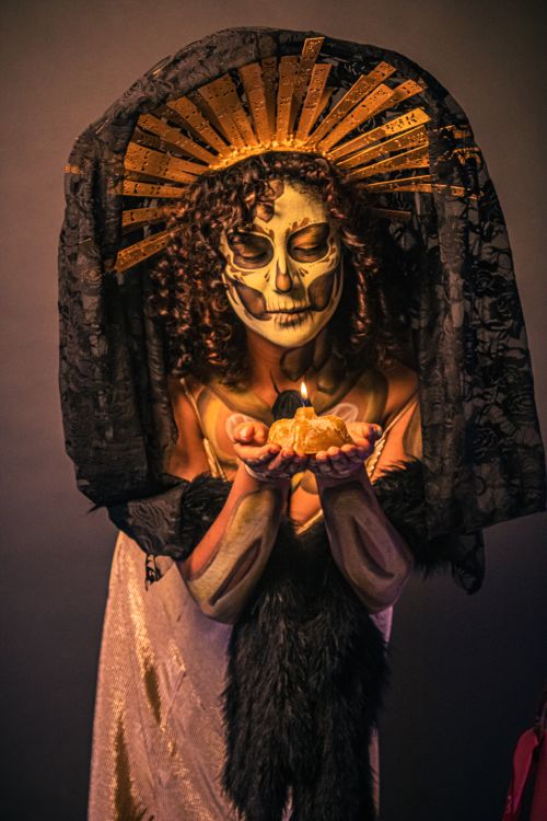 Free Catrina inspired woman in ornate headdress holding cempasuchil flower, celebrating Dia de Muertos. Stock Photo