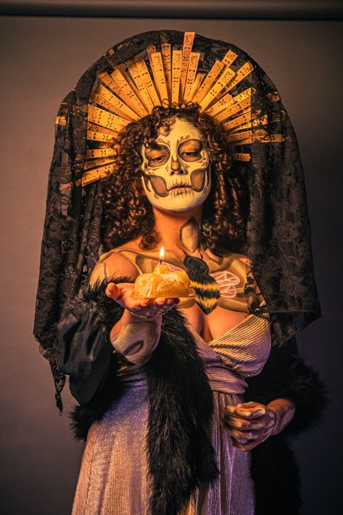 Free A woman in ornate Catrina makeup and headdress holds a lit candle for Day of the Dead. Stock Photo