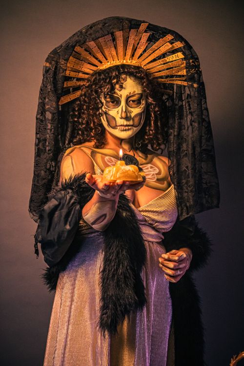 Free Woman in Day of the Dead attire holding cempasuchil, featuring ornate headdress and makeup art. Stock Photo