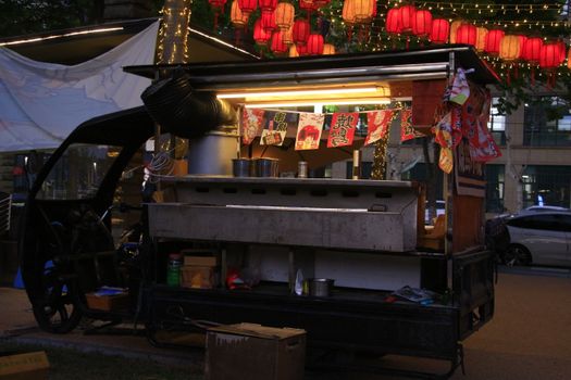 Colorful street food cart adorned with lanterns in an Asian night market setting.