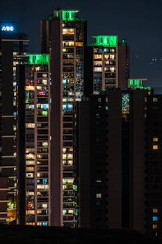 High-rise buildings with vibrant lights illuminating the night cityscape, offering a modern urban perspective.