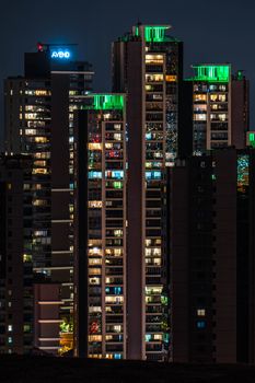 Vivid night view of skyscrapers with glowing green lights in a vibrant cityscape.