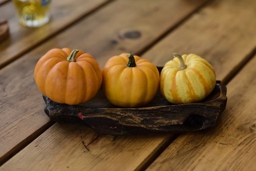 Free Three mini pumpkins on a wooden tray create a cozy autumn scene. Stock Photo