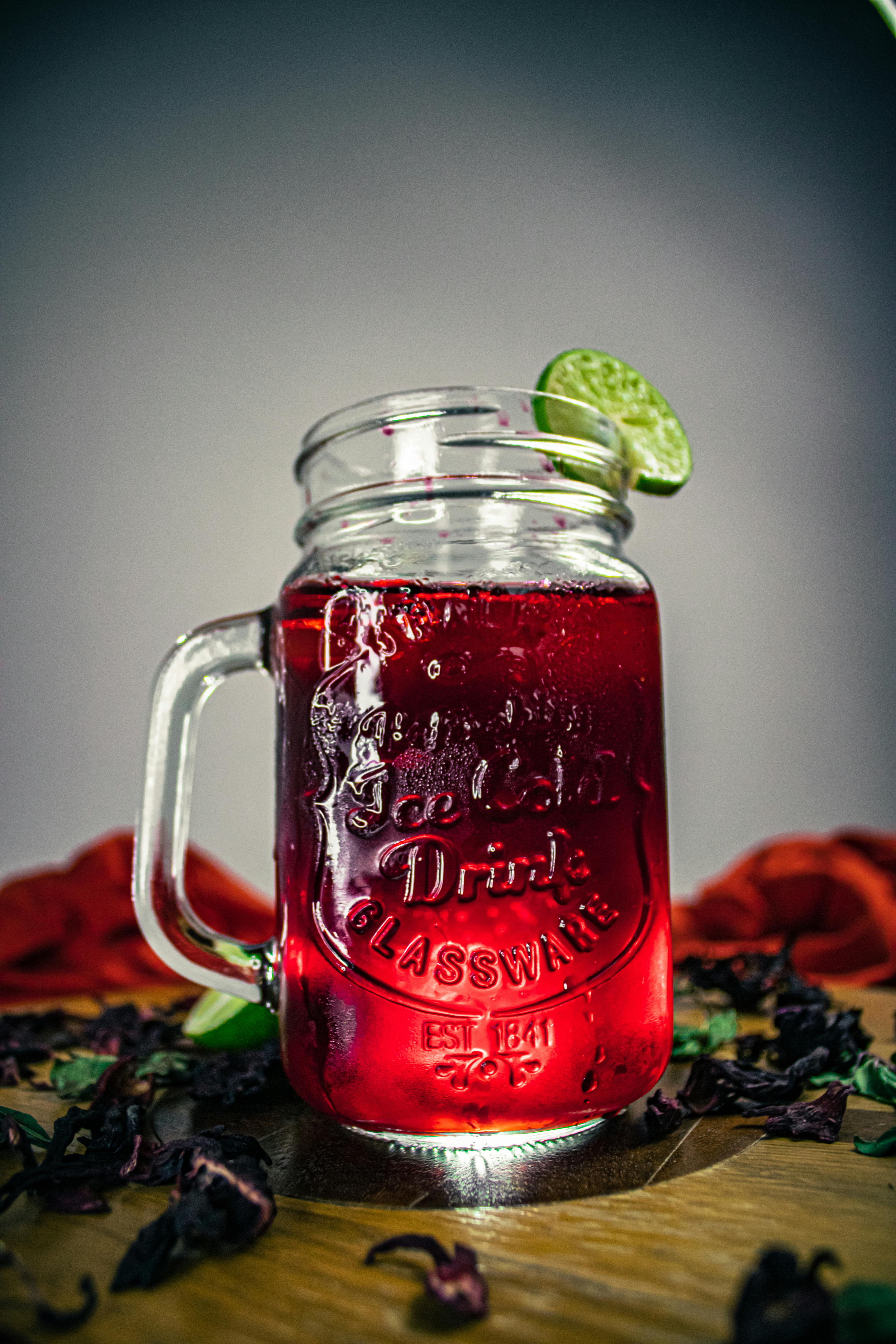 Jus de bissap rouge vif dans un mason jar avec tranche de citron vert