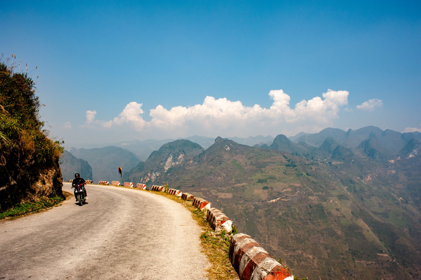 Motorcyclist on a winding mountain road near Ma Pi Leng Pass in Ha Giang