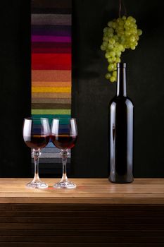 Sophisticated wine bottle and glasses with grapes against a colorful backdrop. Perfect for wine lovers.