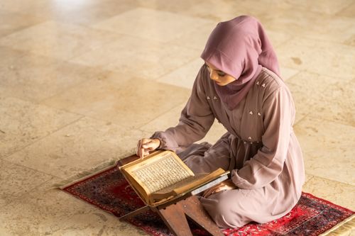 Free Elegant woman in hijab reading the Quran at a mosque in Jakarta, Indonesia. Stock Photo