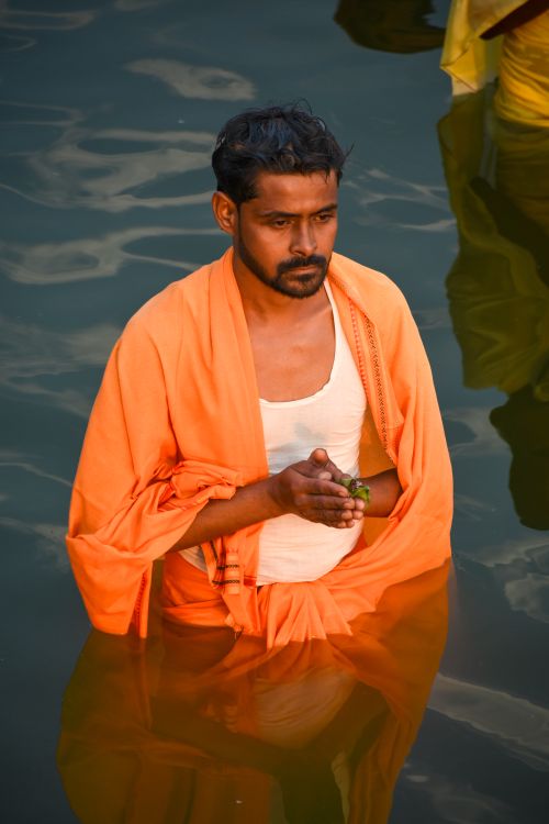 Free Man performs a spiritual ritual in sacred river water, wearing traditional attire. Stock Photo