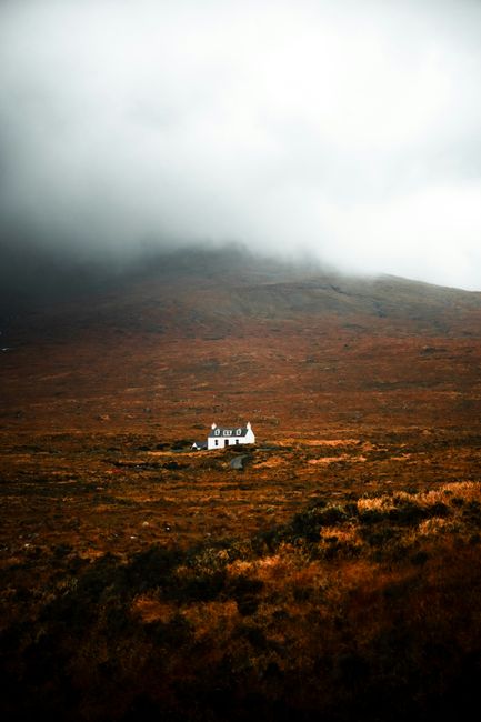 A solitary house in the misty Scottish Highlands during fall season.