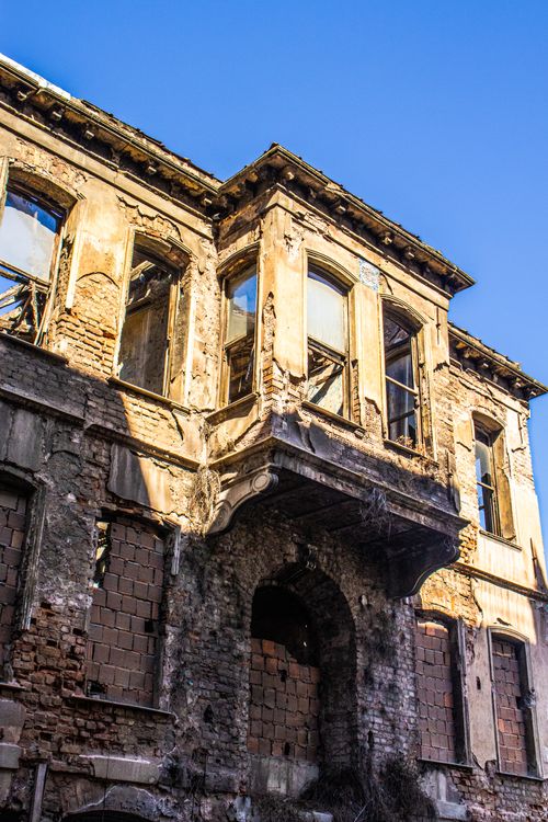 Free A decaying historic building with weathered bricks and windows, captured under a clear blue sky. Stock Photo