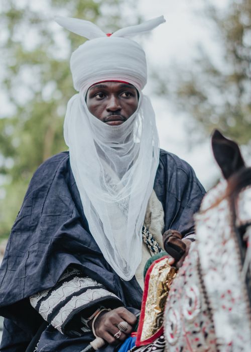 Free An adult African man wearing traditional attire, riding a horse outdoors. Stock Photo