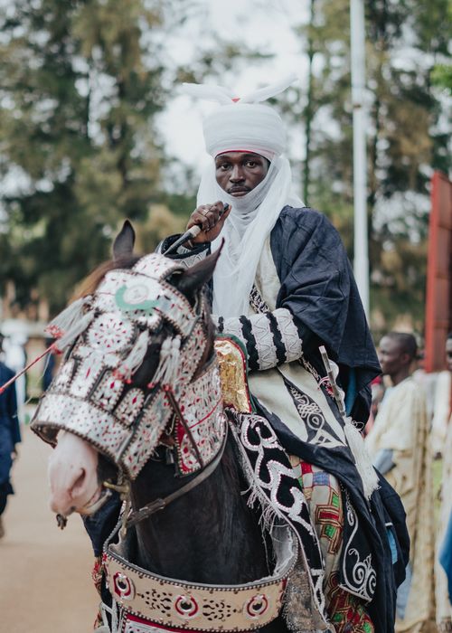 Free Man in traditional African attire riding a decorated horse at a cultural festival. Stock Photo