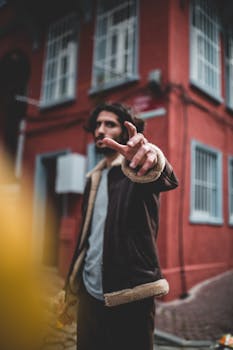 一位年轻人穿着时尚夹克，自信地在红色建筑前摆姿势