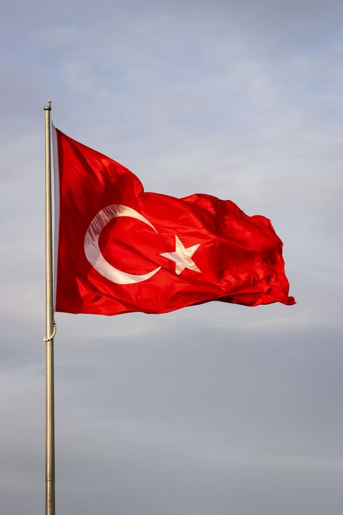 Free Turkish national flag with crescent and star waving in the wind against a clear blue sky. Stock Photo