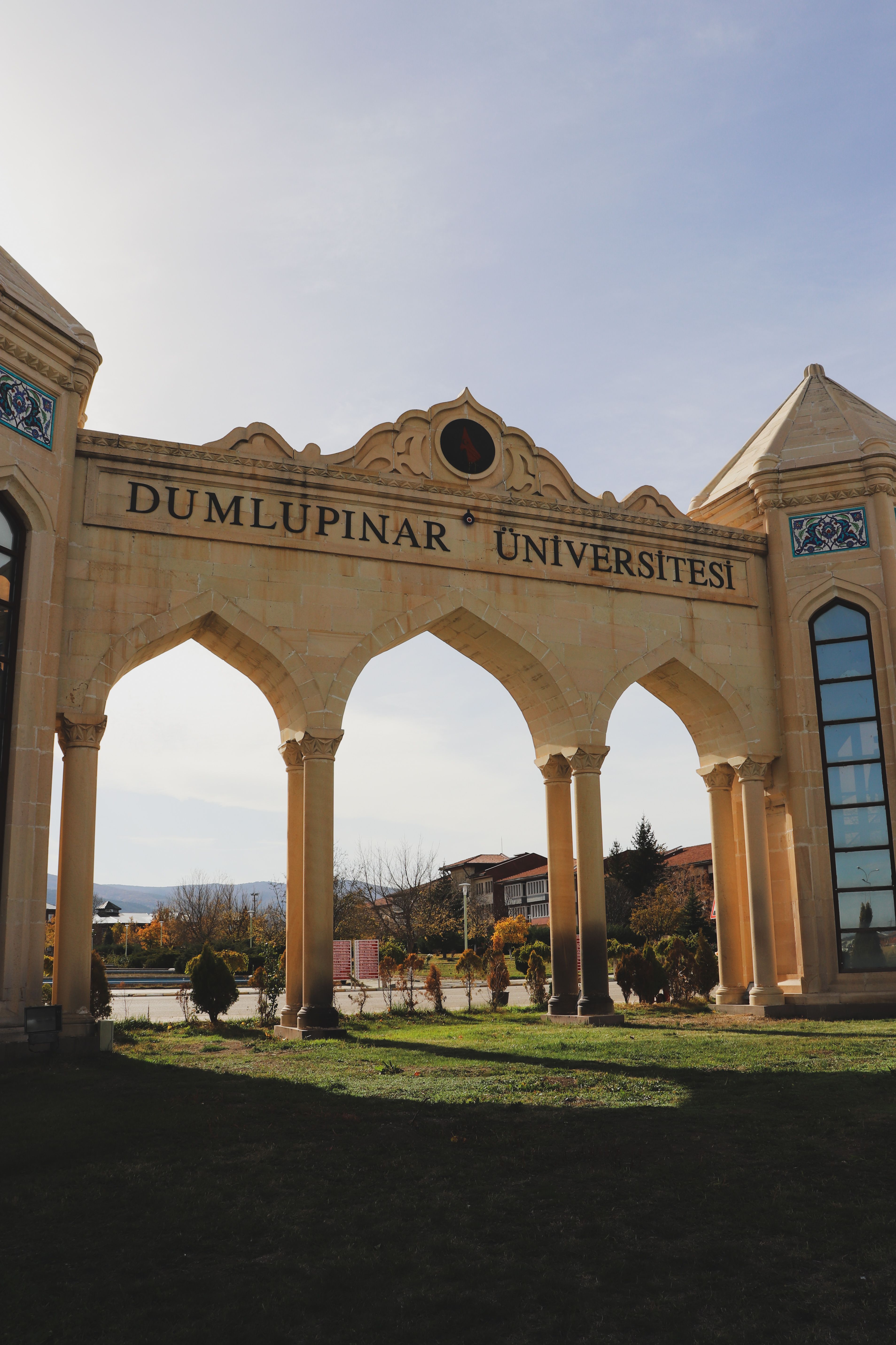 Elegant archway entrance of Dumlupınar University bathed in natural sunlight creating a warm atmosphere.