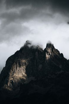 Moody mountain peak enveloped by clouds, highlighting rugged terrain and dramatic skies.