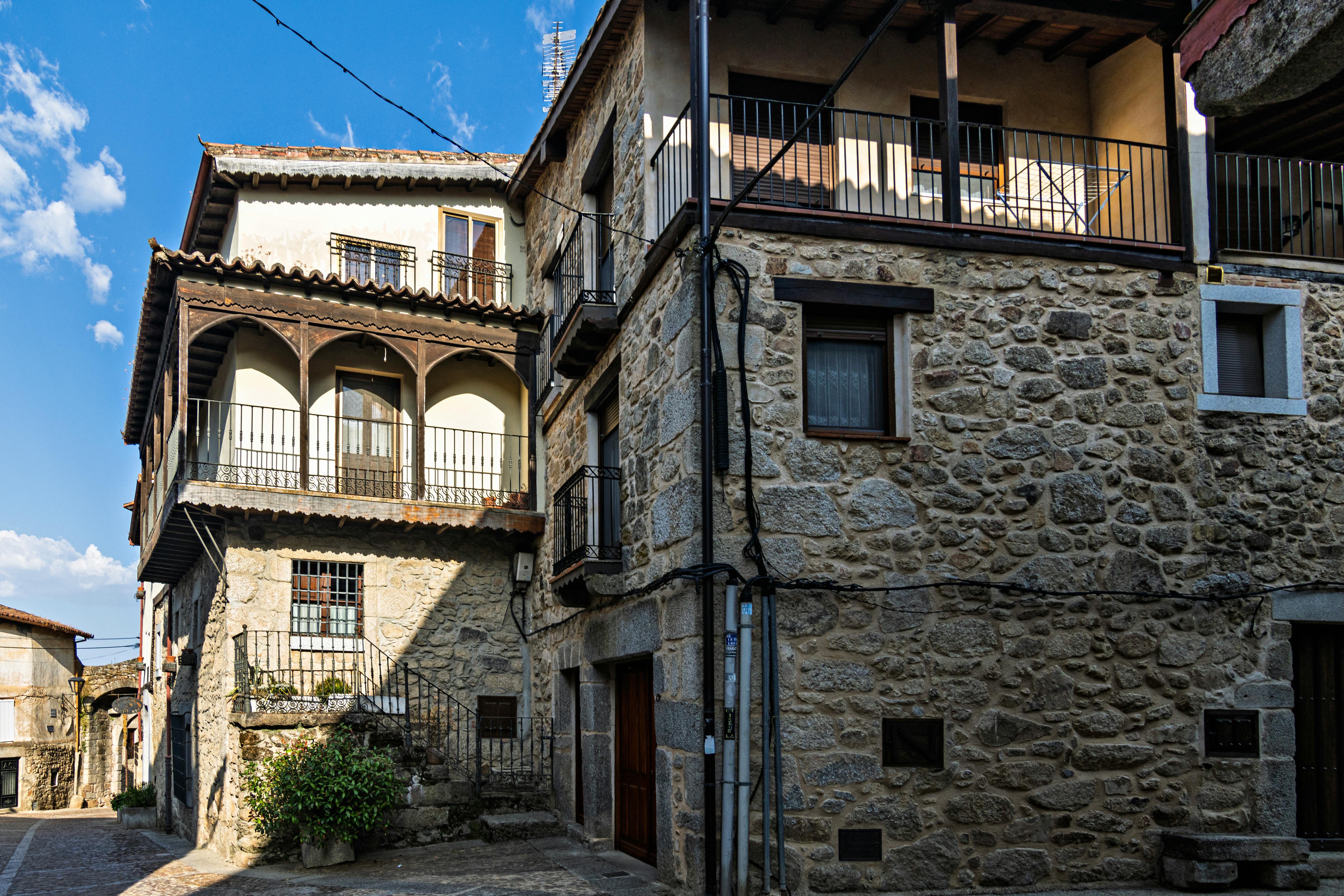 Explore rustic stone houses in a picturesque Spanish village under a sunny sky.