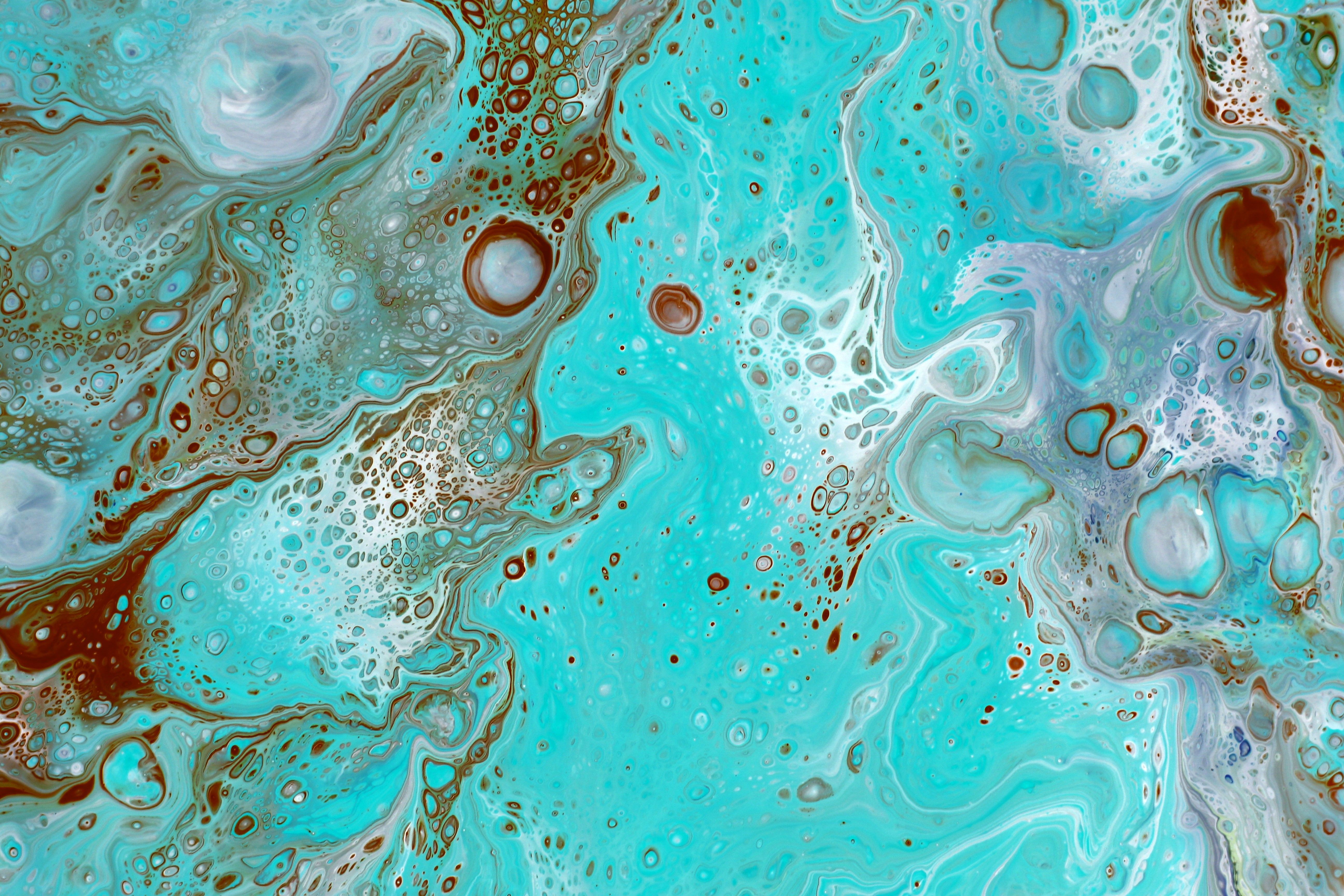 A fluid acrylic pour painting with vivid swirling colours that blend into one another organically