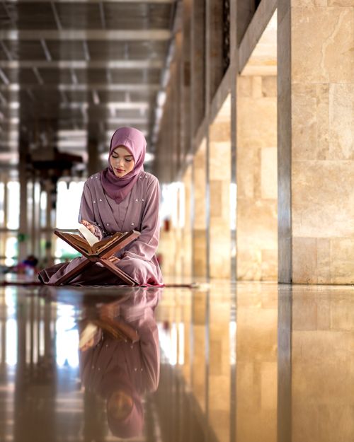 Free Woman in hijab reading Quran inside a mosque in Jakarta, Indonesia. Stock Photo