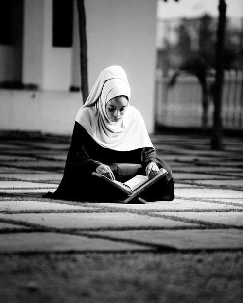 Free Black and white photo of woman in hijab reading outdoors, peaceful and thoughtful scene. Stock Photo