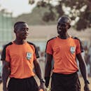Two Soccer Referees in Orange Jerseys Walking